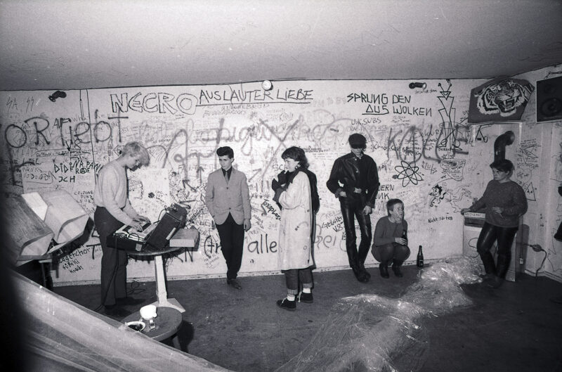 Geniale Dilletanten Alex Hacke playing with Kiddy Citny (in the band Sprung aus den Wolken) to a small audience: Silvie Langenfeld (3rd from left), Blixa Bargeld (Einstürzende Neubauten, 4th from left), Risiko, Berlin, 1981. Photo: Anno Dittmer