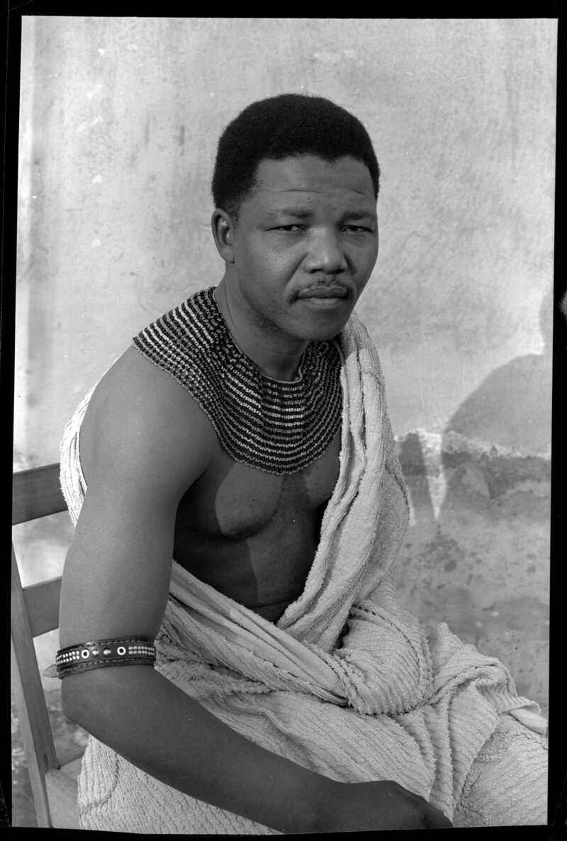 Eli Weinberg: Porträt von Nelson Mandela mit traditionellen Perlenketten und einem Betttuch. Er versteckte sich vor der Polizei während seiner Zeit als "Black Pimpernel", 1961 Courtesy of IDAFSA