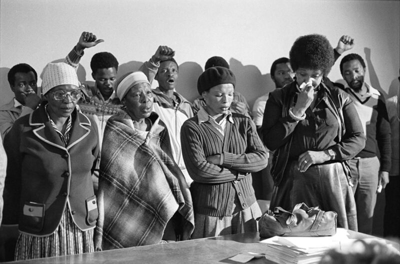 Gille de Vlieg: Pauline Moloise (Mutter von Ben Moloise), zwei weitere Frauen und Winnie Madikizela Mandela trauern bei der Gedenkfeier für Benjamin Moloise, der an diesem Morgen durch den Strang hingerichtet worden war, Khotso House, Johannesburg, 18. Oktober 1985 © Gille de Vlieg