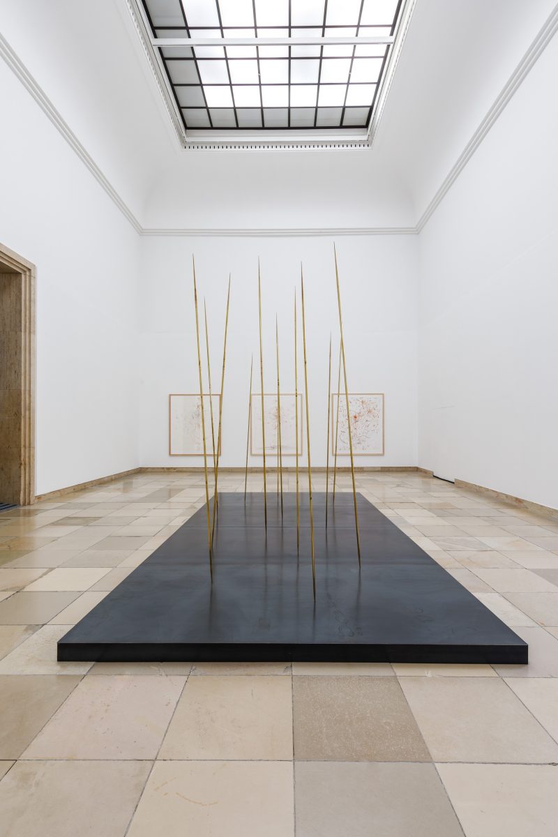 Messingstäbe auf einer großen dunklen Platte im Ausstellungsraum.