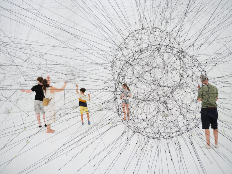 Installation aus mit Spinnennetzen aus Schnüren in der Personen stehen