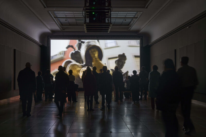 Viele Menschen stehen vor einem Bildschirm.