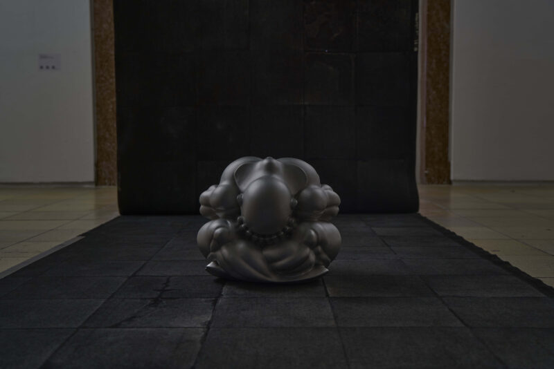 Auf einem schwarzen Teppich liegt eine runde Figur.