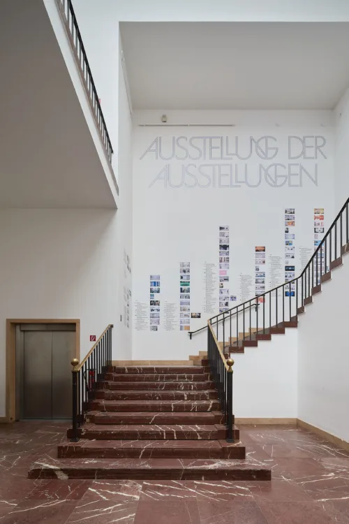 An der Wand, hinter einer Treppe, sind mehrere kleine Bilder angebracht.