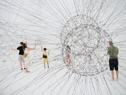 Installation aus mit Spinnennetzen aus Schnüren in der Personen stehen
