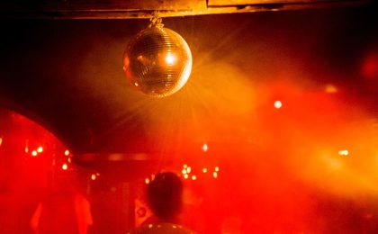 Eine rot beleuchtete Tanzfläche mit Disko-Kugel.