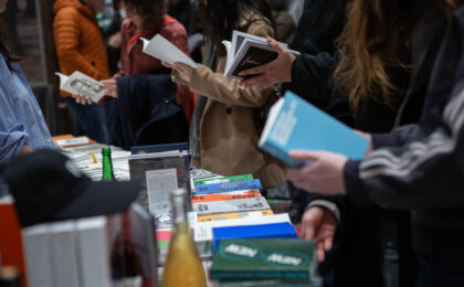 Menschen schauen an einem Stand Bücher und Zeitschriften durch.