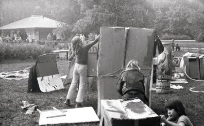 Ein schwarz-weiß Foto, auf welchem Kimder mit Pappkartons spielen.