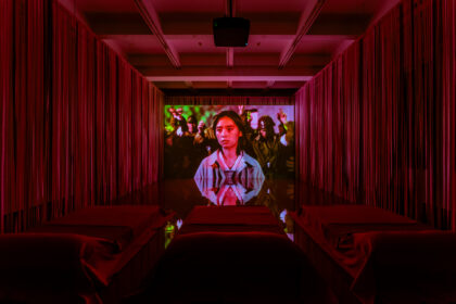 In einem roten Kinosaal wird ein Film abgespielt.