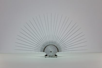 In einem weißen Raum befindet sich eine metallene Fächerartige Skulptur.