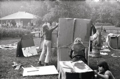 Ein schwarz-weiß Foto, auf welchem Kimder mit Pappkartons spielen.