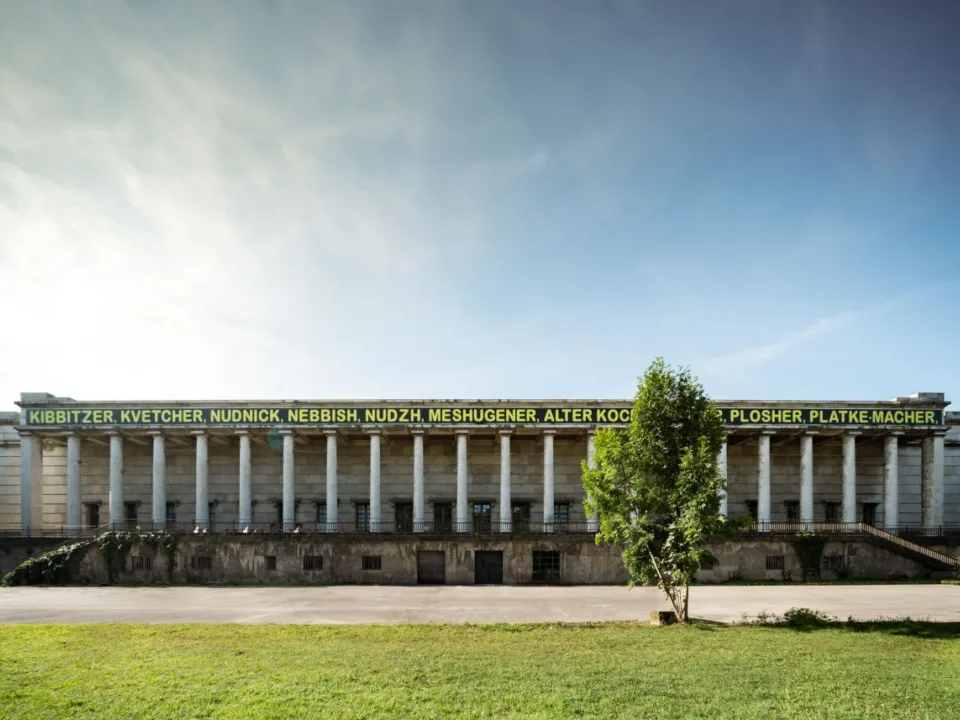 Eine Hausfassade hinter einer Wiese.