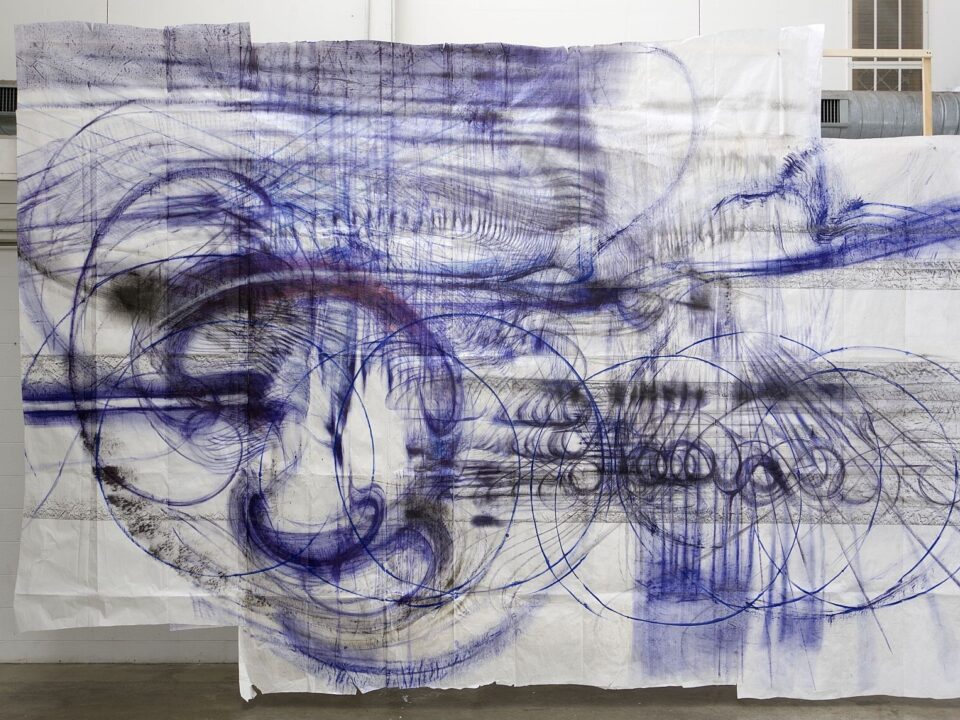 Weiße Tüche hängen von der Decke mit blauen Zeichnungen darauf.