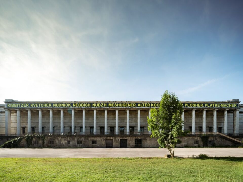 Eine Hausfassade hinter einer Wiese.